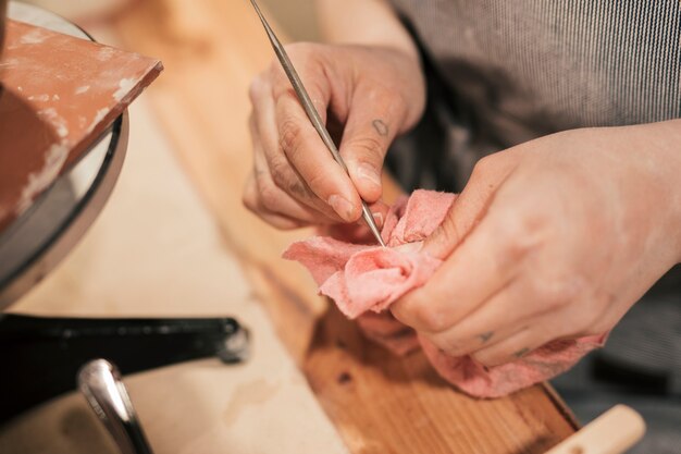 Close-up of female potter's hand cleaning the tool with napkin