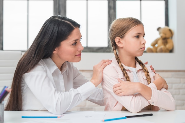 Close-up of female psychologist comforting her depressed little girl