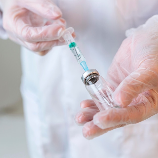 Close-up of female researcher with gloves holding syringe