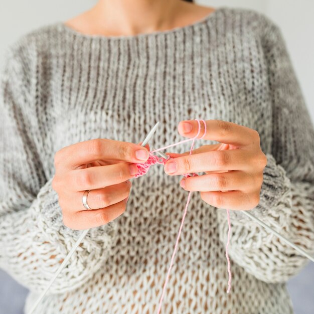 ピンク色の糸でかぎ針編みの女性の手のクローズアップ