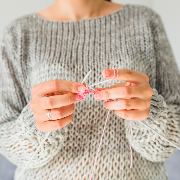 Крупный план руки женщины вязание крючком с розовой нитью