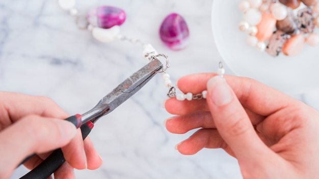 Close-up of a female's hand fixing the metallic ring with pliers