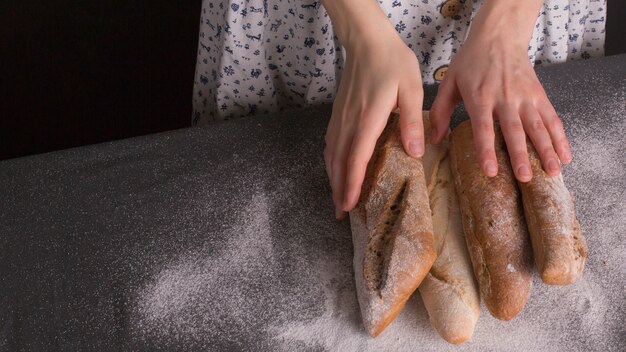 Close-up of female's hand holding fresh baked baguettes on kitchen counter