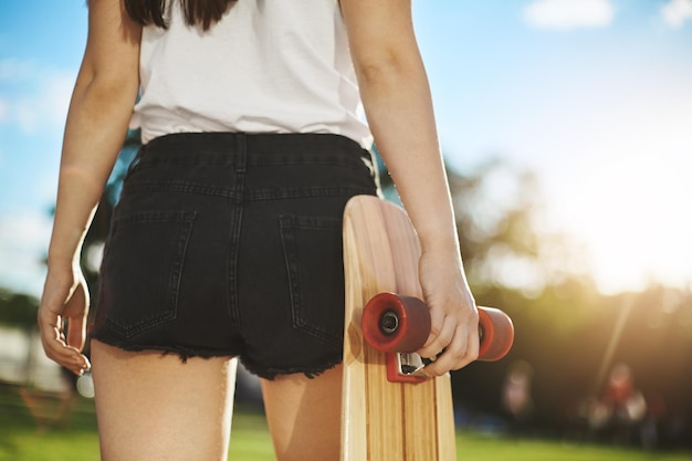 Close up of female skateboarder having fun in park holding her longboard