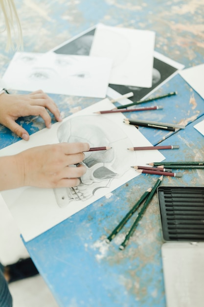 Close-up of female sketching skeleton with pencil on workbench