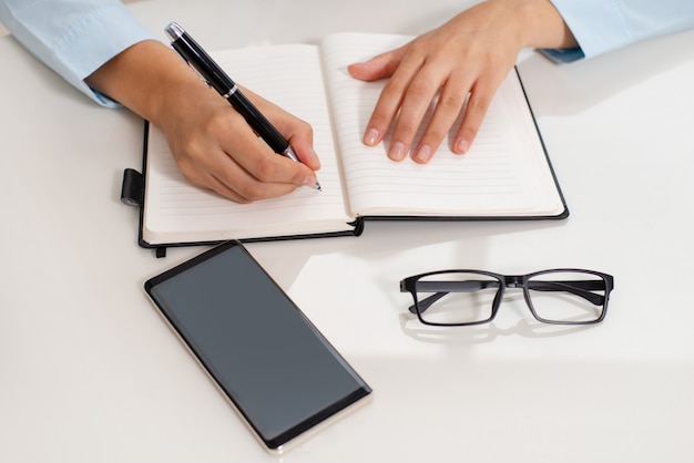 Free photo close-up of female teachers hands making notes in workbook