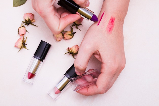 Free photo close-up of female testing different lipsticks on hand over white backdrop