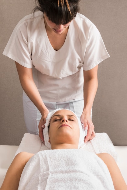 Крупный план женского терапевта обертывание полотенце на голову женщины