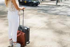 Foto gratuita primo piano del turista femminile che sta sulla borsa e sul passaporto di viaggio dei bagagli della tenuta della strada