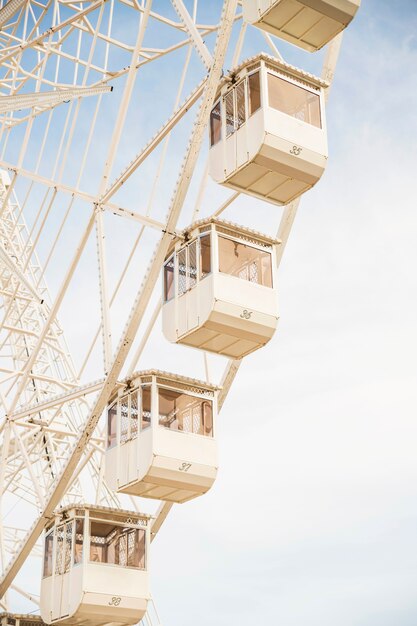 Close-up of ferris wheel white cabins against blue sky