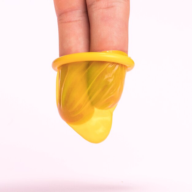 Close-up fingers in a yellow condom