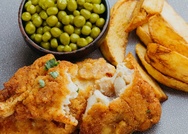 Primo piano di pesce e patatine fritte con piselli