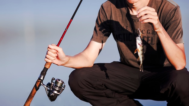 Foto gratuita primo piano di un pescatore con la cattura e la canna da pesca fresche