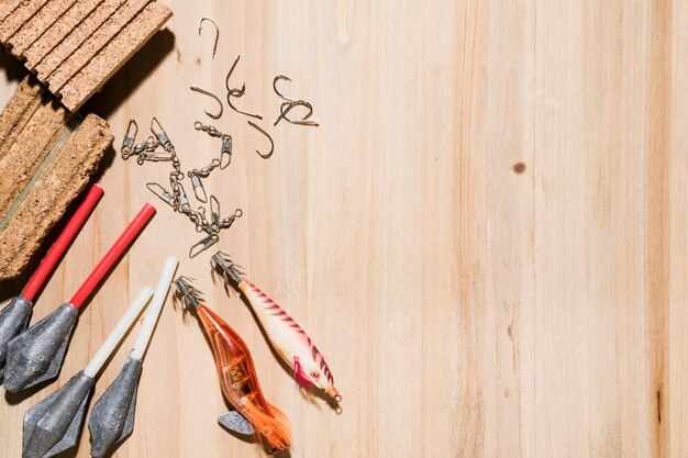 Close-up of fishing hook; fishing lure; cork with fishing line and sinkers on wooden backdrop