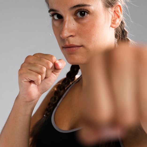 Close-up fit woman in combat position with blurred hand