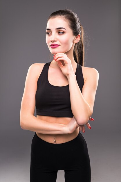 Close up of fit woman's torso with her hands on hips on grey wall