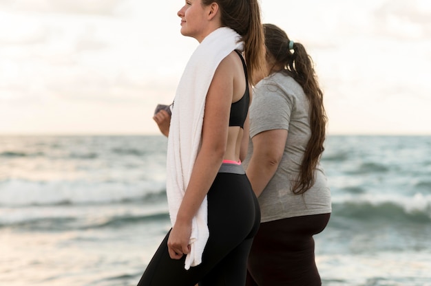 Close-up fitness friends walking on shore