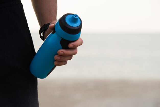 Close-up of fitness shaker bottle in male hand
