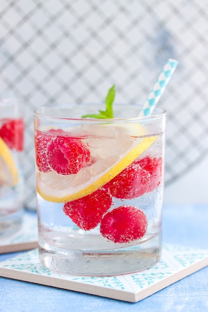 Close-up of fizzy drink with raspberries and slice of lemon