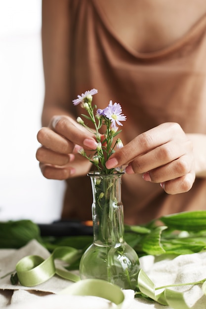 Close up of florist hands making bouquet of flowers at workplace.