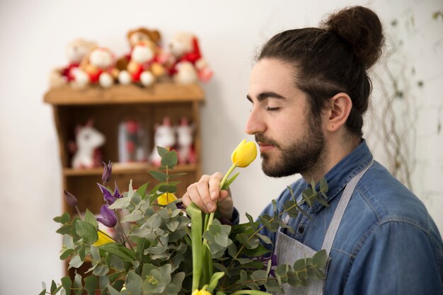 Крупный план флориста мужчина, пахнущий цветок тюльпана в букете