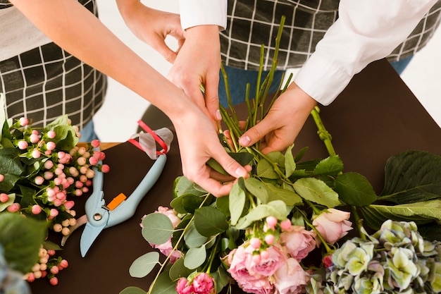 Close-up florists making bouquet with roses