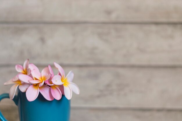 Close-up of flowers on blue mug and wooden background