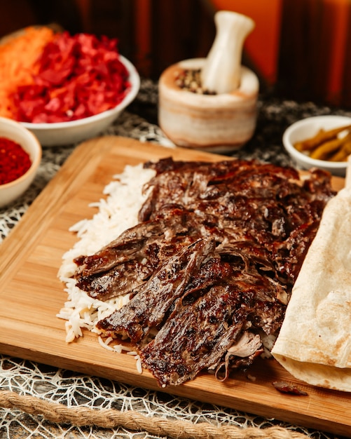 Close up fo lamb doner kebab place on rice served with flatbread