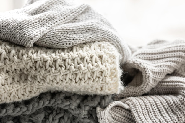 Close up of folded knitted items of grey color on a light background