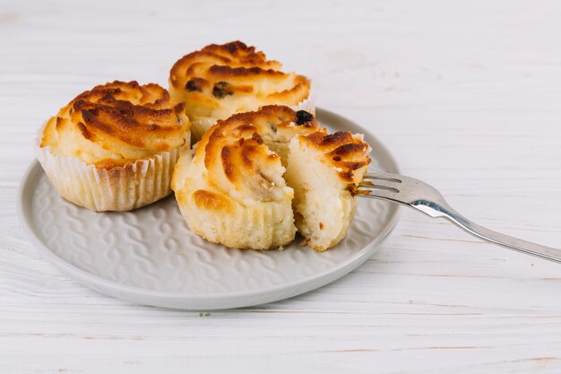 Close-up of fork in the cupcake on plate over the wooden backdrop