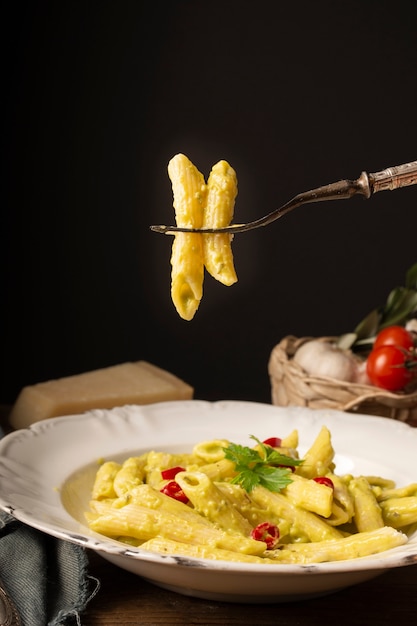 Close up fork and penne with pesto and red peppers