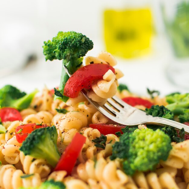 Close-up of fork with broccoli; tomato and fusilli