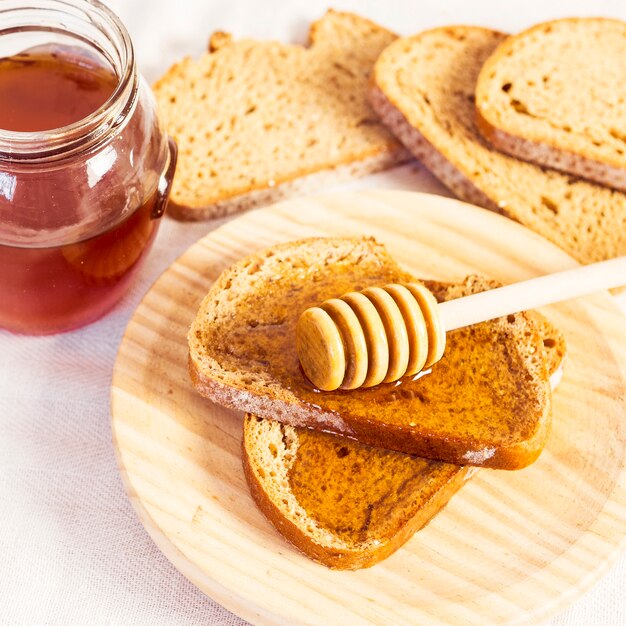 Close-up of fresh bun slice with honey in wooden plate