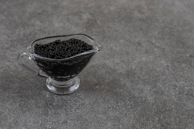 Close up of fresh caviar in glass bowl over grey surface