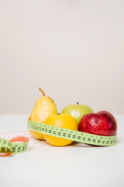 Close-up of fresh fruits with measuring tape on table