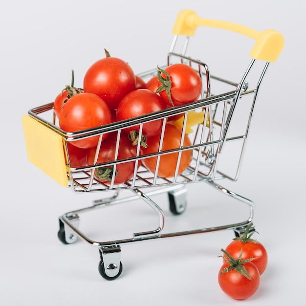 Close-up of fresh tomatoes in trolley on white surface