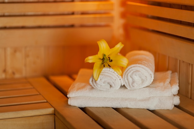 Close up fresh towels and yellow lily in sauna