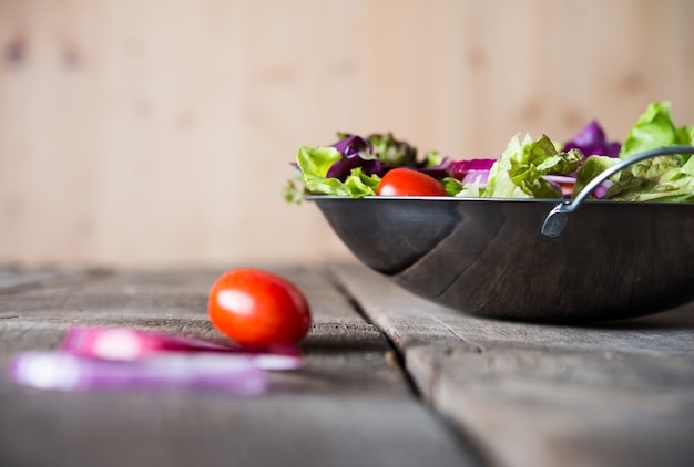 Close up of fresh vegetables salad in the bowl with rustic old wooden background. Healthy food concept.