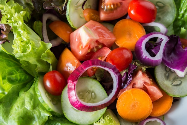 Закройте свежий салат из овощей в миске с деревенским старым деревянным фоном. Концепция здоровой пищи.
