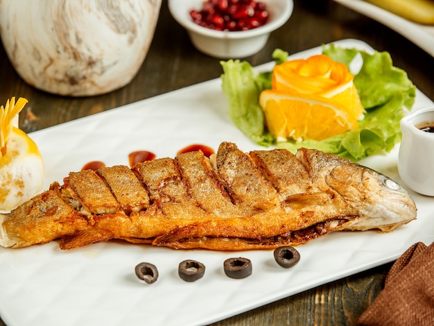 Close up of fried whole fish served with sauce