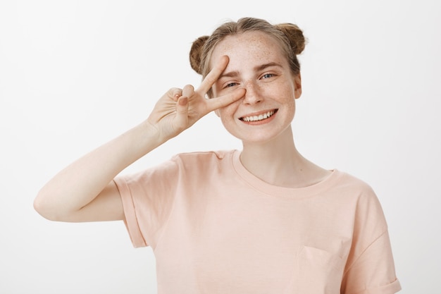 Foto gratuita primo piano dell'adolescente felice sorridente amichevole della testarossa che mostra il gesto di pace