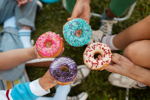 Free photo close up on friends eating donuts