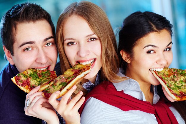 Close-up of friends eating a tasty pizza