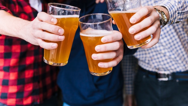 Close-up of friends hand clinking the beer glasses