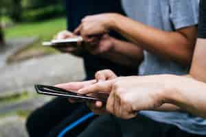 Free photo close up of friends hands play with smartphone together.