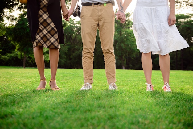 Close up of friends' legs in keds on grass.