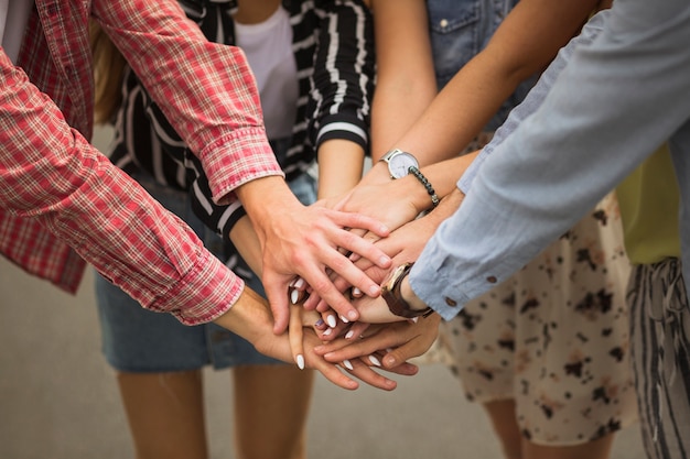 Close-up of friends putting hands on top of each other