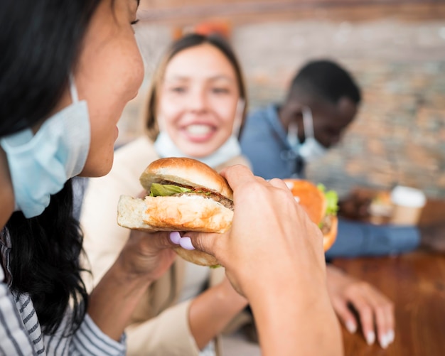 Free photo close-up friends with masks and burgers