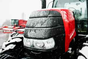 Free photo close up in front of the new red tractor at snowy weather