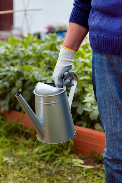 Free photo close-up gardener holding sprinkler in garden